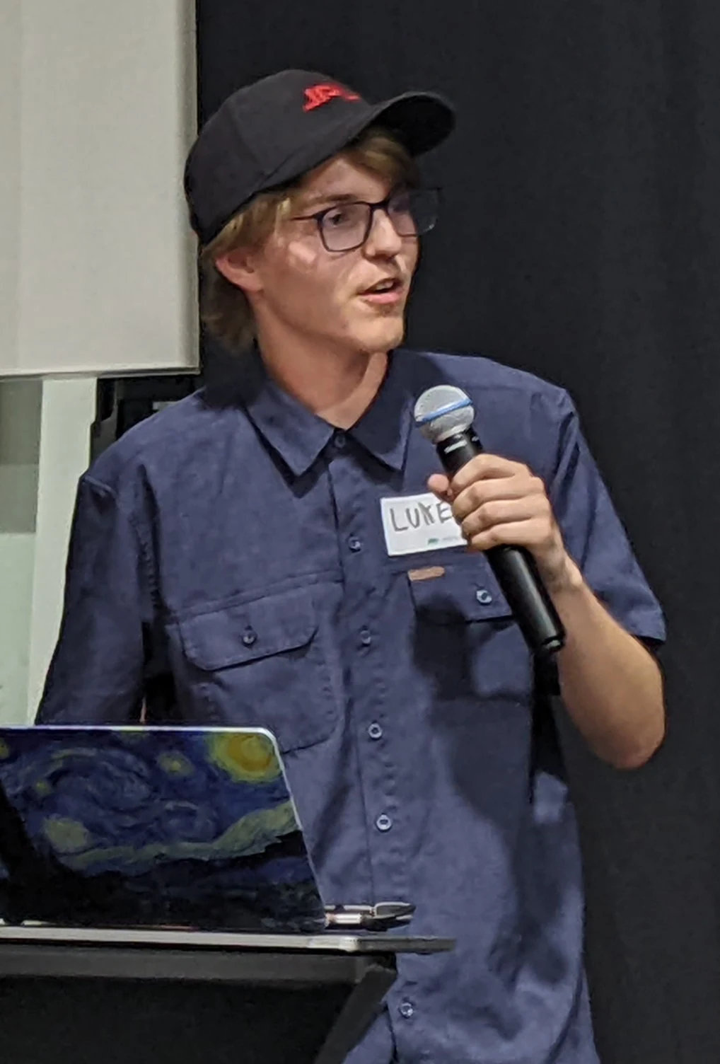 Luke Farritor holds a microphone while presenting at a technology meetup