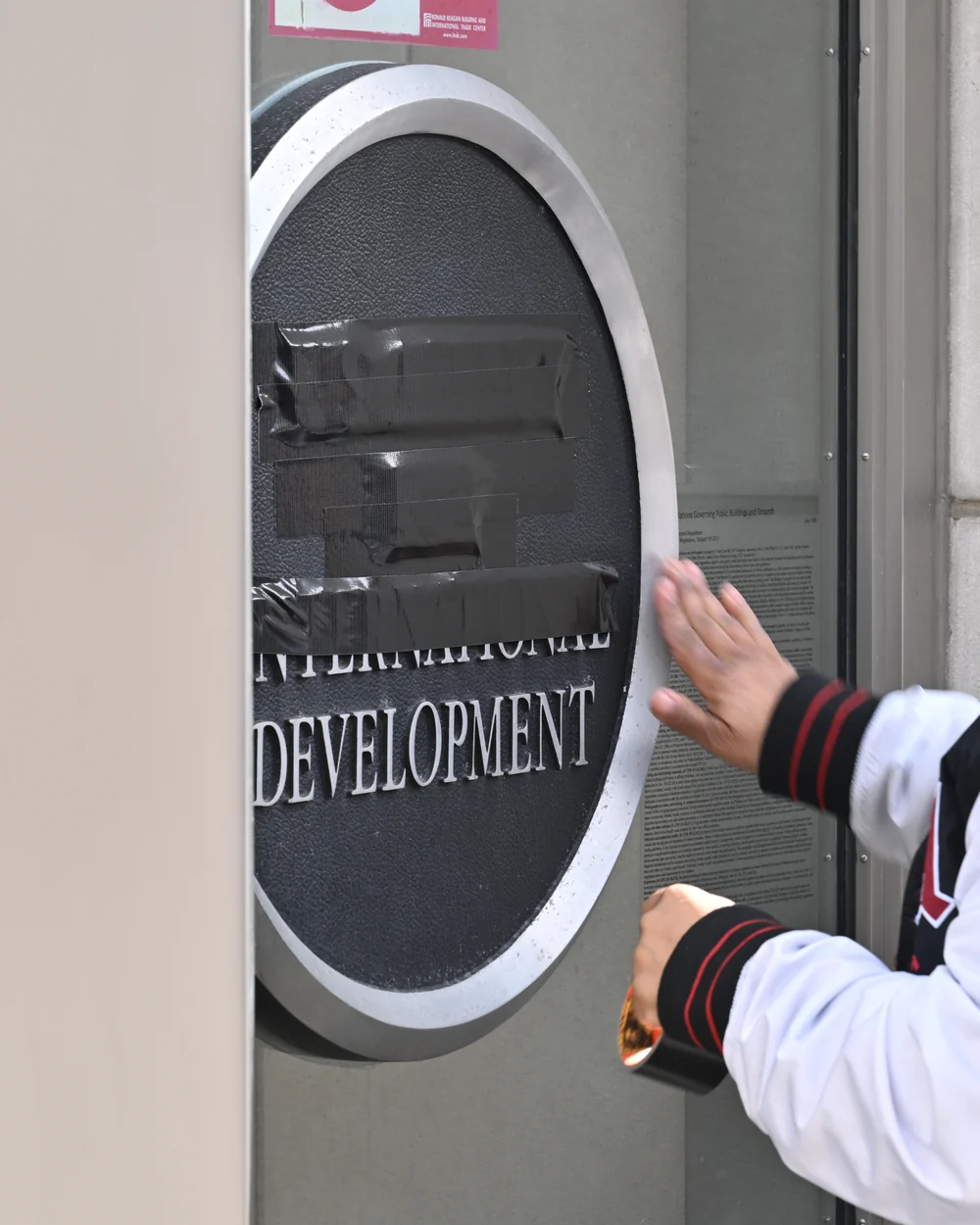 A worker covering the USAID sign on the Ronald Reagan Building